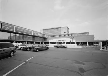 Image of a indoor shopping mall built during urban renewal in Southwest. Early 1970 cars are parked in the foreground while the shopping complex is in the background making an L shape. Image of a indoor shopping mall built during urban renewal in Southwest. Early 1970 cars are parked in the foreground while the shopping complex is in the background making an L shape.